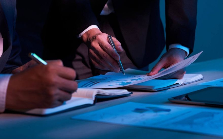 Hand hält Stift über Finanzdokument