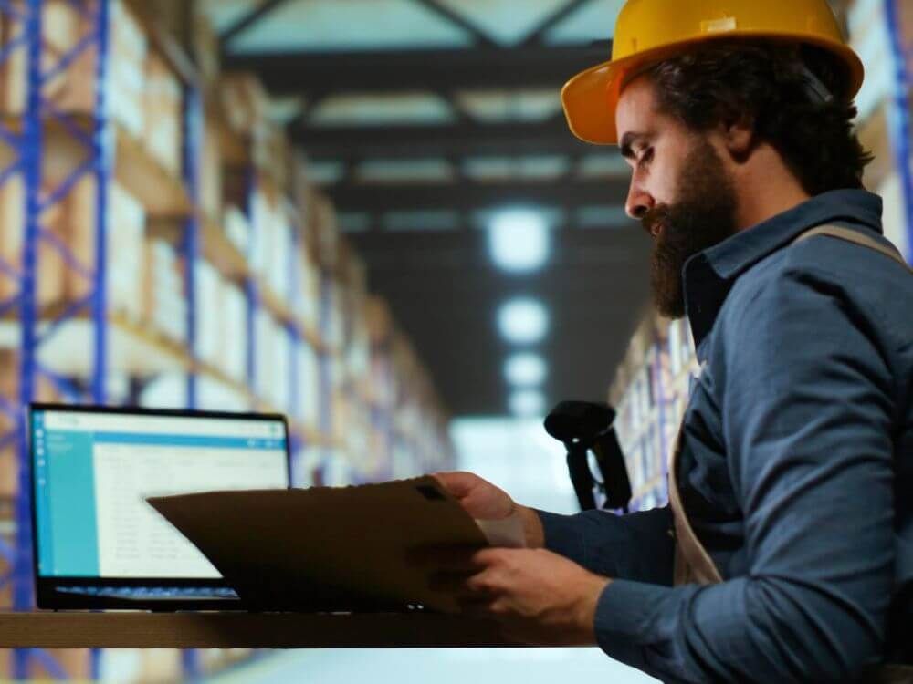 Mann bei der Arbeit im Lager vor Computer sitzend
